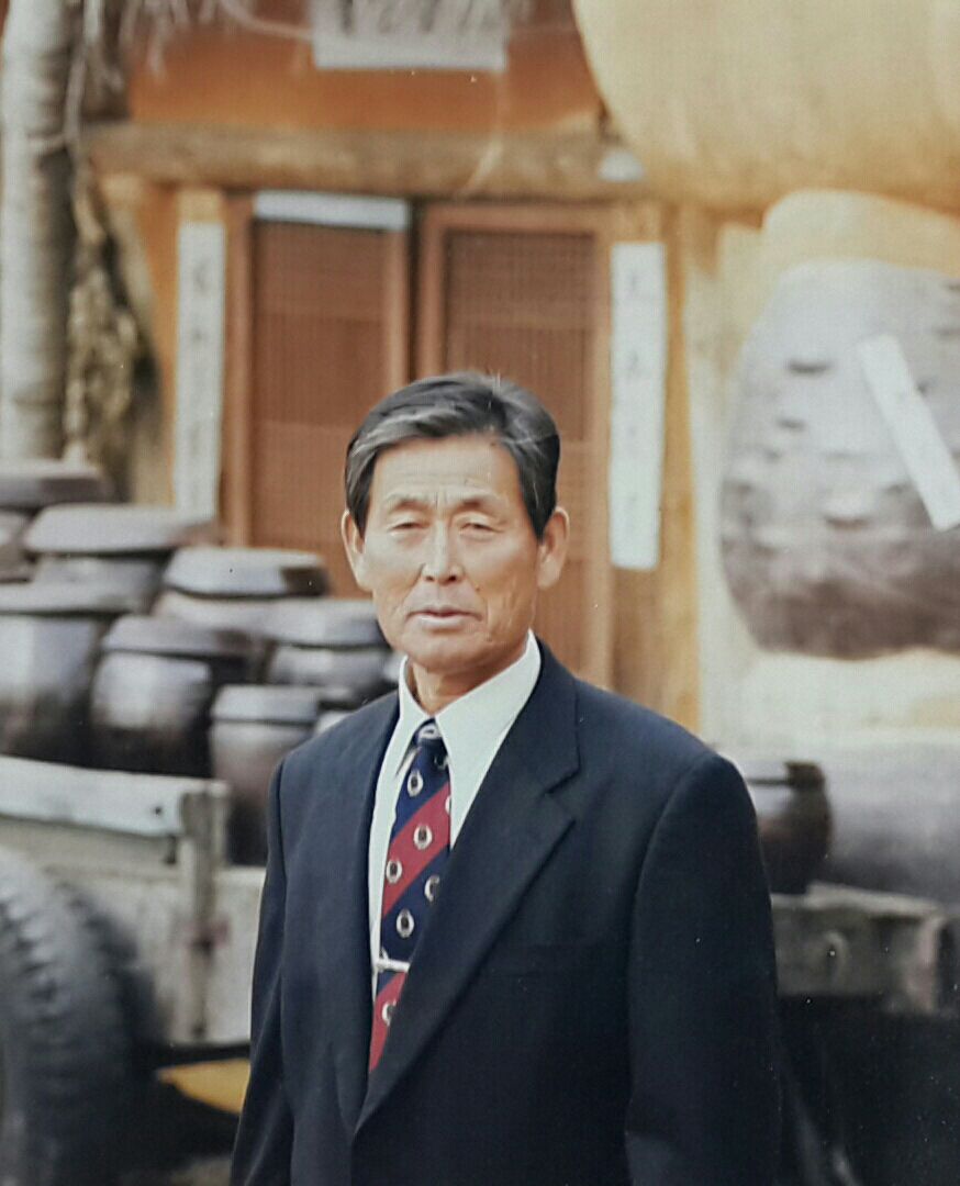 장독대가 있는 마당에 정장을 입고 서 있는 이태옥의 오래된 컬러 사진